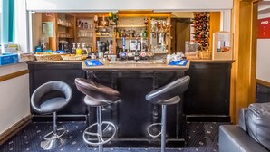 A bar area with two stools, a clock, and a wine rack. - OYO Stade Court Hotel (Hythe)