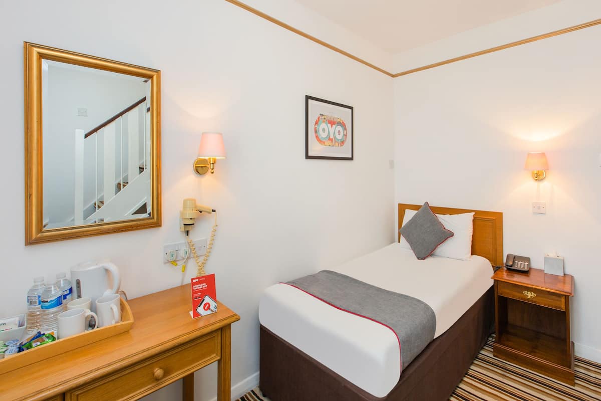 Una habitación de hotel con cama, mesita de noche, lámpara y un cuadro en la pared.