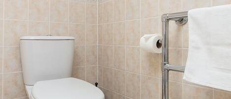 A bathroom with a toilet, a towel rack, and a toilet paper holder.