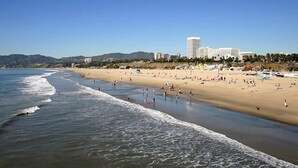 Een strand met mensen, een zandstrand en gebouwen op de achtergrond.
