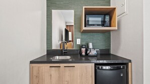 Een moderne keuken met een zwart aanrecht, houten keukenkastjes, een inbouwplank voor de magnetron en een vaatwasser.