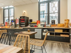 Un café moderne avec un comptoir, un espace salon et de grandes fenêtres.