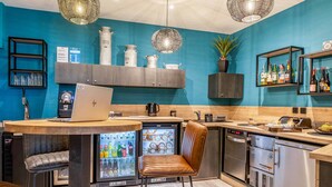 Eine moderne Küche mit Laptop auf der Arbeitsfläche, einem Kühlschrank und einer Kaffeemaschine.