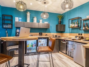 Une cuisine moderne avec un ordinateur portable posé sur le plan de travail, un réfrigérateur et une machine à café.