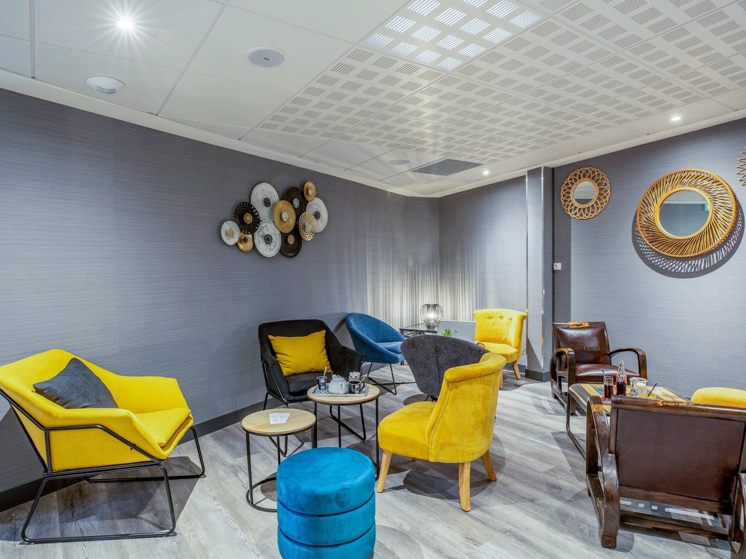 A modern lounge with contemporary furniture, a patterned ceiling, and decorative wall art.