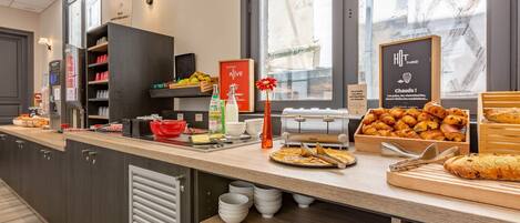 A breakfast buffet area with a variety of food items, a toaster, and a sign indicating gluten-free options.