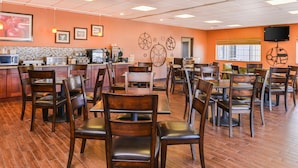 A restaurant with wooden chairs and tables, a counter with a coffee machine, and decorative wall art.