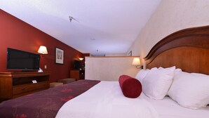 A hotel room with a bed, a television, and a desk with a lamp.