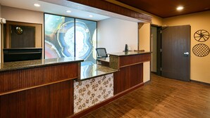 A reception desk with a wooden finish, a glass partition, and a mosaic tile design.