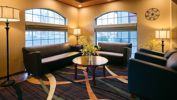A lobby with a sofa, chairs, a coffee table, and lamps.