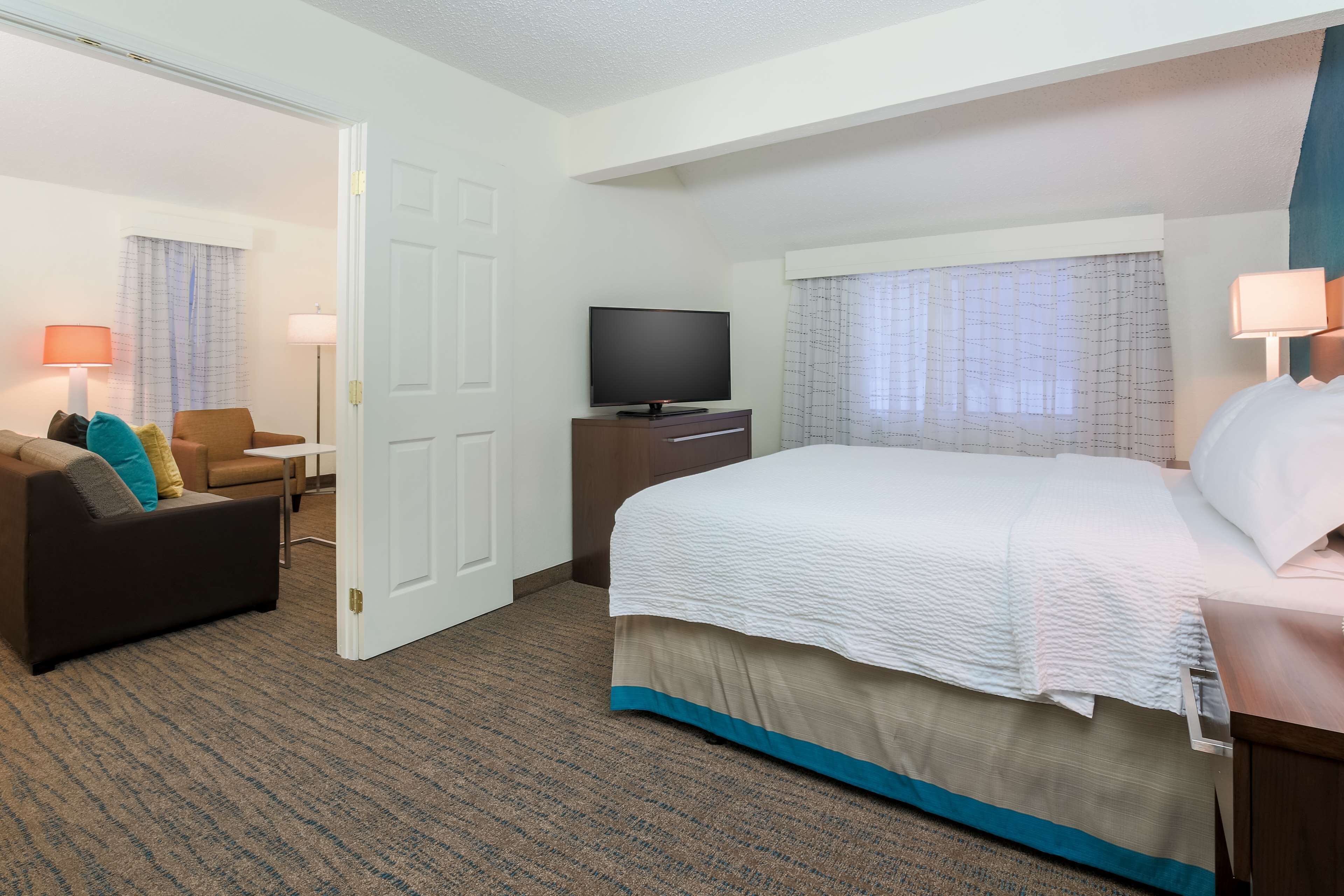 Une chambre d’hôtel avec un lit, une télévision, un bureau et une chaise.