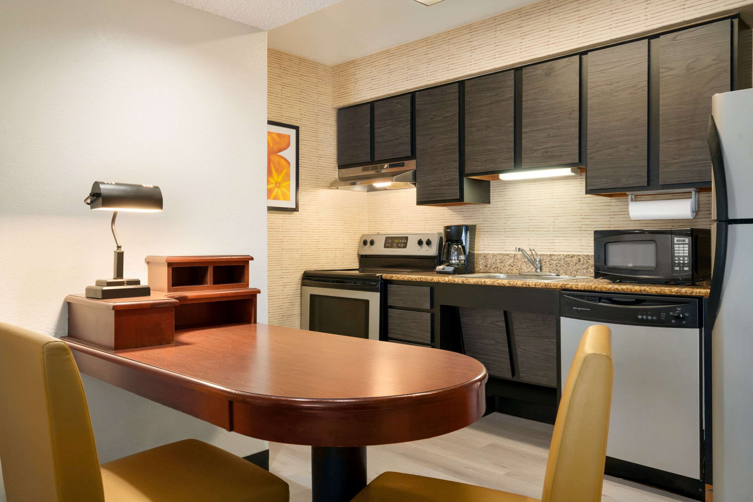 A modern kitchen with dark cabinets, a microwave, a coffee maker, and a dishwasher.