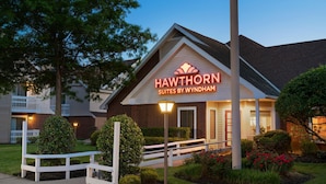 Un hôtel appelé Hawthorn Suites by Wyndham, doté d’une pelouse bien entretenue et d’une clôture en bois peinte en blanc.