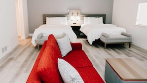 Une chambre d’hôtel avec deux lits, un canapé rouge et une petite table en bois.