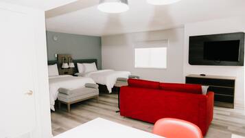 A hotel room with a bed, a red sofa, a TV, and a desk.