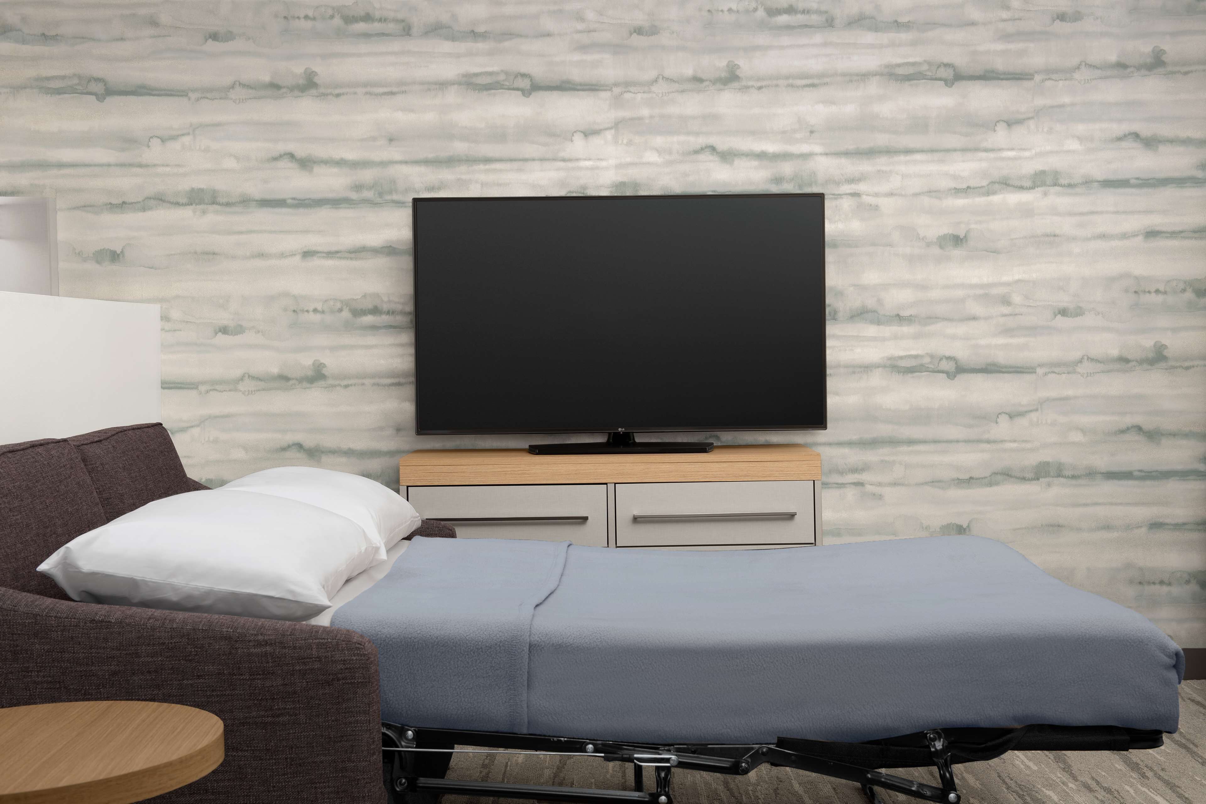 A room with a bed, a TV, a couch, and a small table.