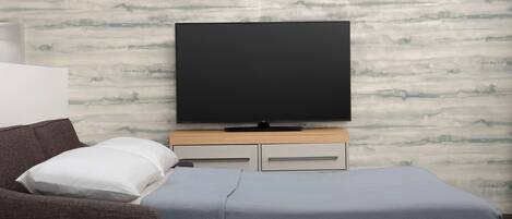 A room with a bed, a TV, a couch, and a small table.