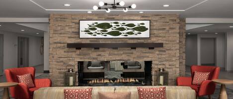A modern living room with a stone fireplace, red upholstered chairs, and a sofa with patterned cushions.