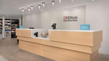 A reception desk at Hilton Garden Inn with a modern design, a self-service kiosk, and a minibar area.