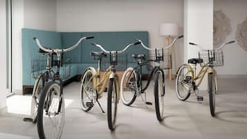 A room with teal-colored sofas, a chandelier, and three bicycles with baskets.