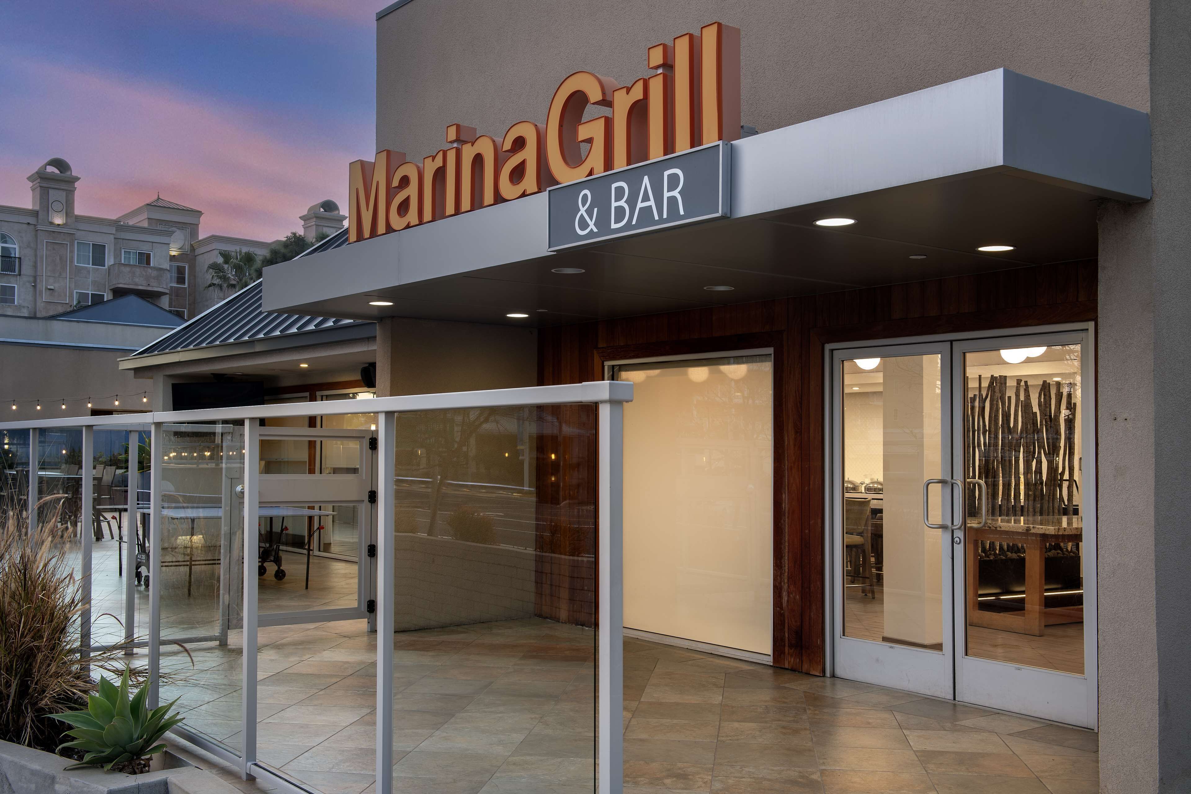 Marina Grill & Bar mit moderner Fassade, großen Glasfenstern und einer Terrasse mit Sitzgelegenheiten.