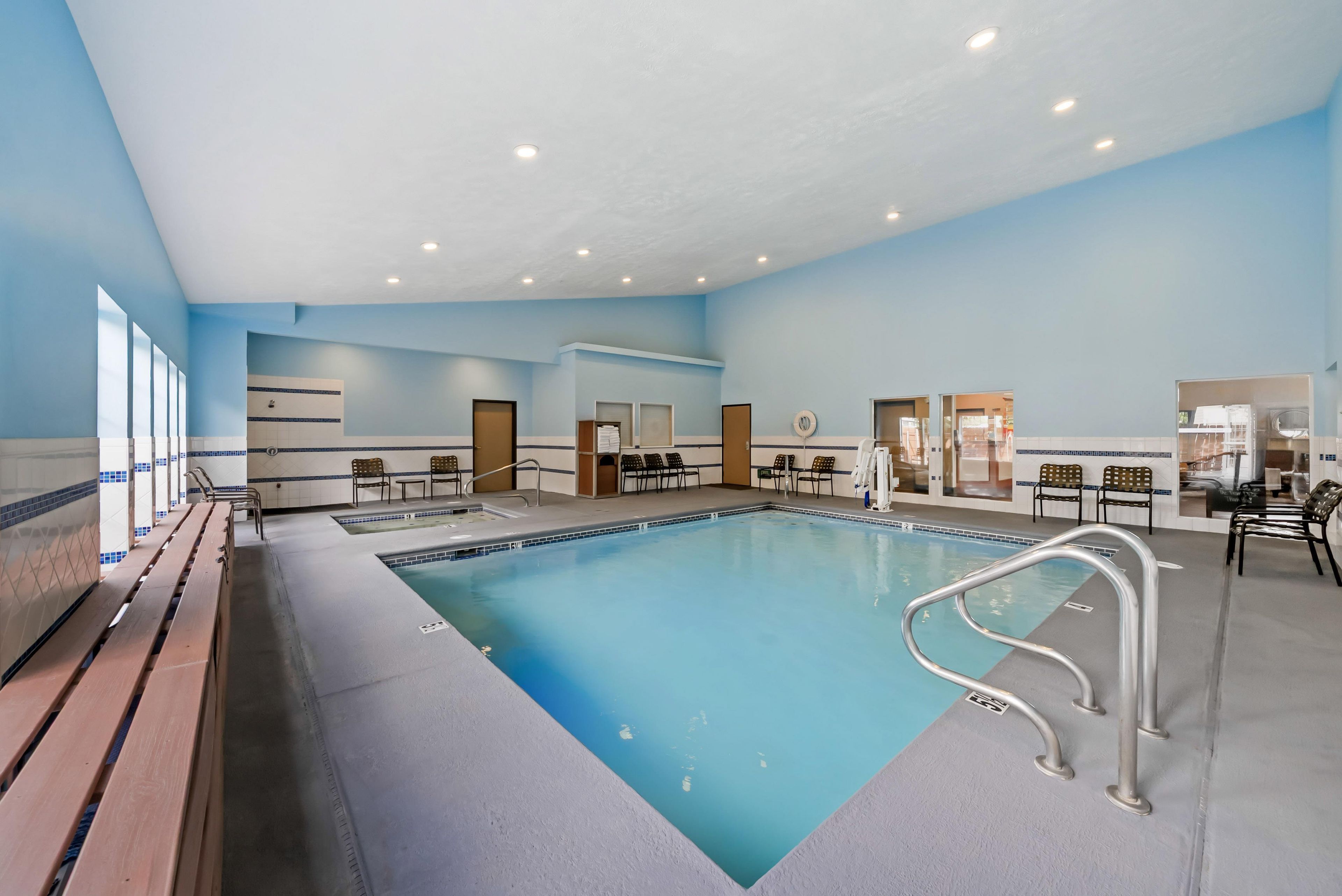 A large indoor swimming pool with multiple lanes, surrounded by lounge chairs and a seating area.