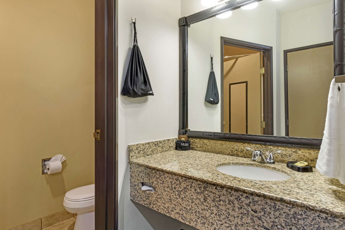 A bathroom with a granite countertop, a sink, a mirror, a towel rack, and a toilet.