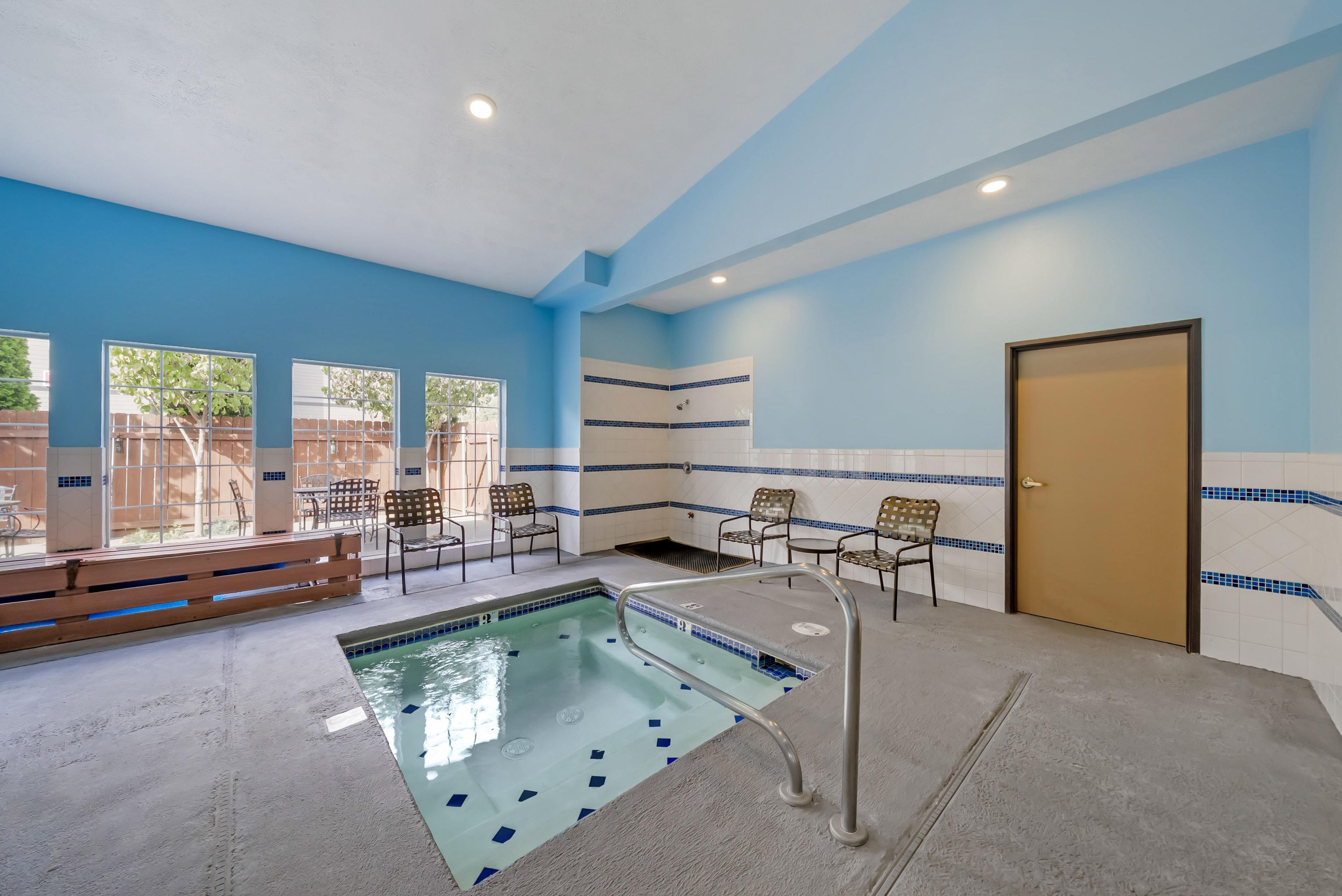 A pool area with a clear view of the pool, a bench, and chairs.