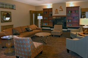 A cozy living room with a brown sofa, patterned armchairs, a round coffee table, and a fireplace. - Best Western Plus The Inn at Horse Heaven (Prosser)