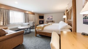 Une chambre d’hôtel équipée d’un lit, d’un canapé, d’une table, d’une télévision et d’une cheminée.