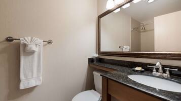 A bathroom with a white toilet, a sink with a mirror above it, and a towel hanging on a metal rack.
