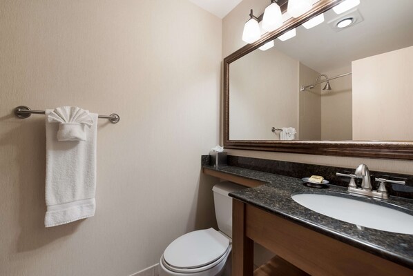 A bathroom with a white toilet, a sink with a mirror above it, and a towel hanging on a metal rack.