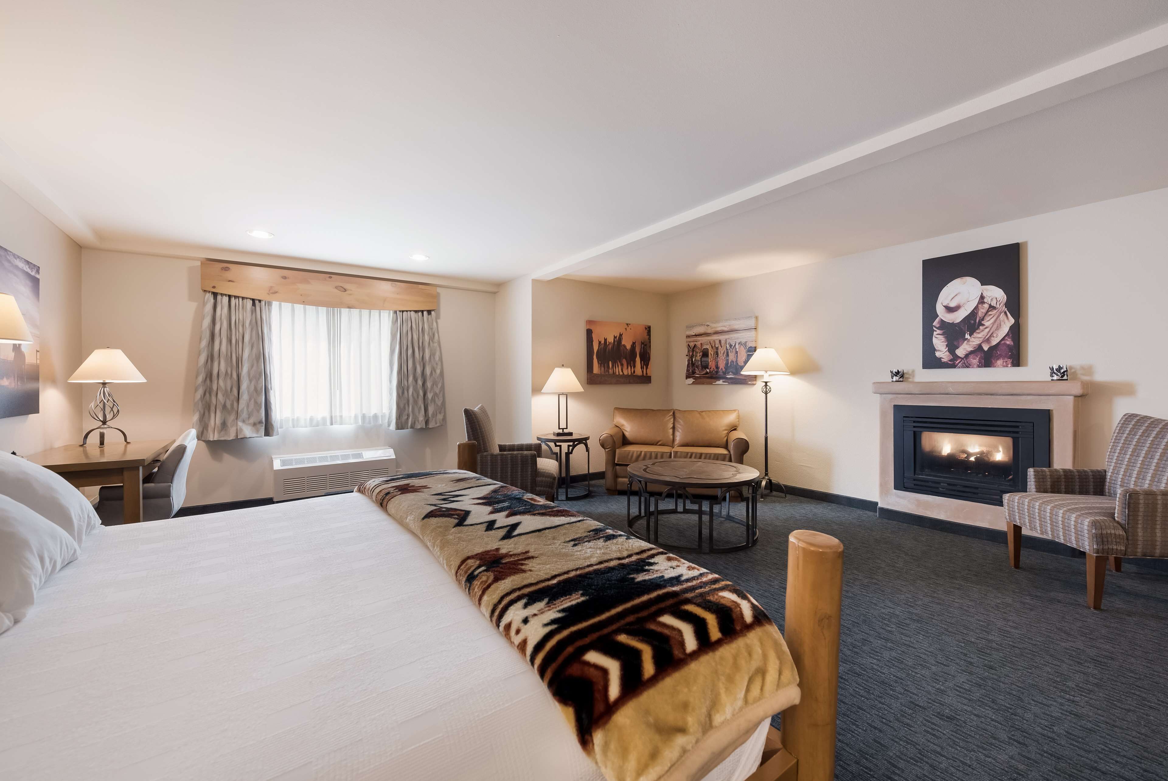 Una habitación de hotel con una cama grande, un sofá, una mesa redonda y una chimenea.