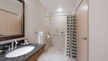 A bathroom with a sink, mirror, shower, and towel rack.