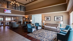 Eine geräumige Lobby mit hoher Decke, einem großen Kronleuchter und einer Sitzecke mit gemusterten Stühlen und einem Sofa.