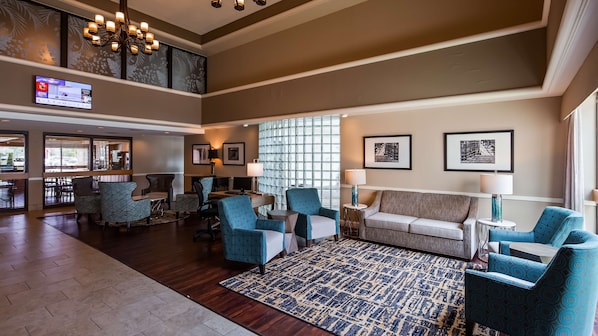A spacious lobby with a high ceiling, a large chandelier, and a seating area with patterned chairs and a sofa.