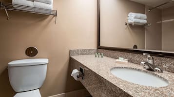 Un baño con inodoro, lavamanos y perchero para toallas.