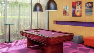 A pool table with balls, two pendant lights, and artwork on the wall.