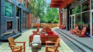 An outdoor patio with seating, a fire feature, and a view of the surrounding buildings. - Aloft by Marriott Lexington (Lexington)