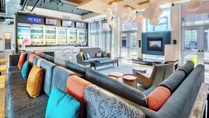 A modern lounge area with sofas, a bar, and a fireplace. - Aloft by Marriott Lexington (Lexington)