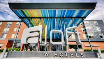 The exterior of the ELOFT W HOTELS with a modern architectural design, large windows, and a colorful striped awning.
