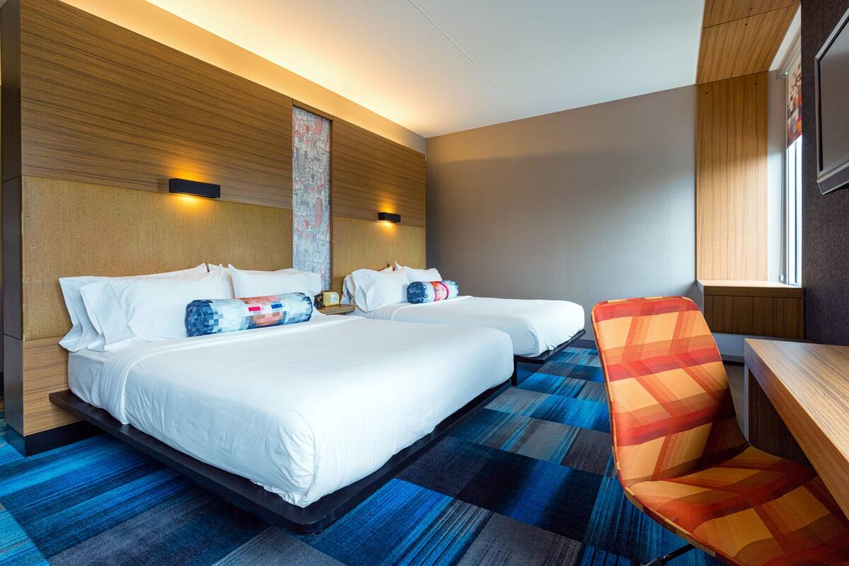 A hotel room with two beds, a sofa, and a wooden headboard.