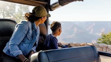 Interior de vehículo con dos pasajeros, un adulto y un niño, mirando un paisaje montañoso.