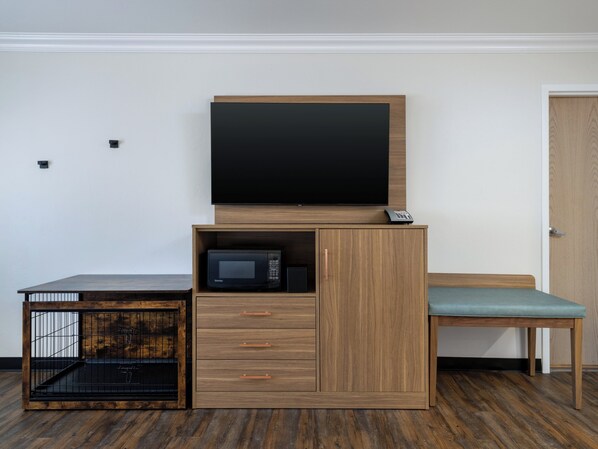 A compact room with a wooden cabinet, a television, a microwave, a small table, and a bench. - Holiday Inn Resort Grand Canyon by IHG (Grand Canyon)