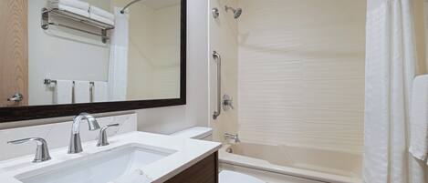 A bathroom with a sink, mirror, toilet, and bathtub.