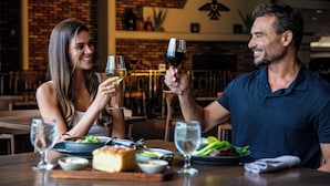 A couple dining at a restaurant with a brick wall and wooden furniture.