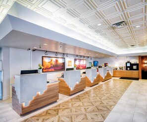 Welcome to our reception area, featuring a spacious desk with wooden accents, framed photographs, and a geometric ceiling design.
