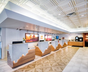 Welcome to our reception area, featuring a spacious desk with wooden accents, framed photographs, and a geometric ceiling design.