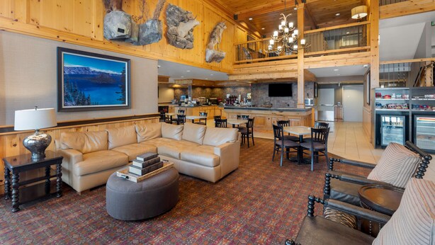 A spacious lobby with a large sofa, dining area, kitchen, and a mounted animal head. - Best Western Plus Olympic Inn (Klamath Falls)