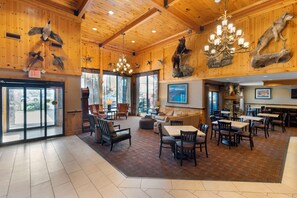 Relax in a cozy central seating area with sofas and chairs, surrounded by mounted animal heads and large windows offering views of the surrounding landscape.